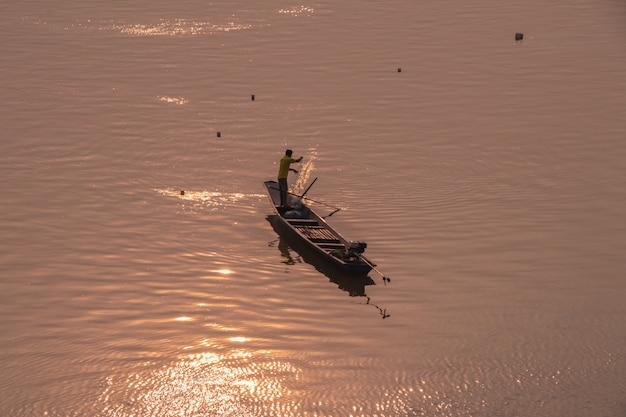 Silhouette of fisherman in boat on the river