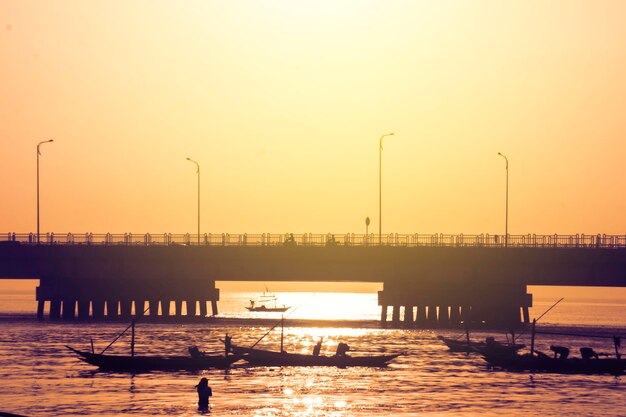 Silhouette of fisherman fishing near Suramadu bridge