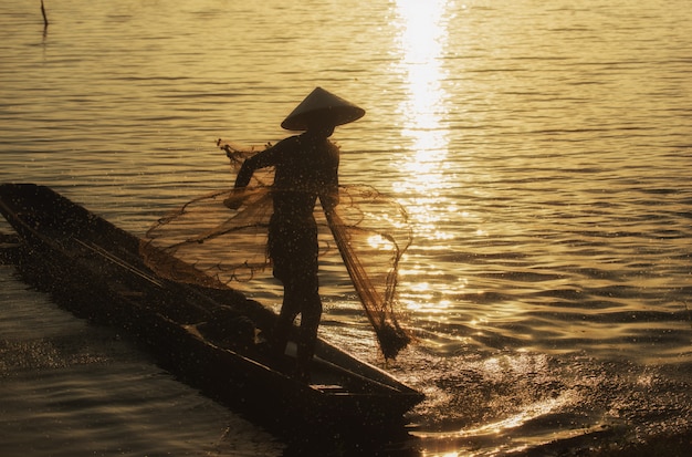 Silhouette Fisherman Fishing Nets on the boat.