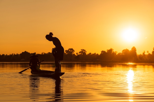 Siluetta del pescatore con rete sul lago al tramonto