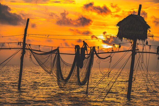 Premium Photo  Silhouette of fishermen casting a nets on fishing poles on  sunrise traditional fishermen prepare the fishing net local people call it  is day hang khoi fisheries and everyday life