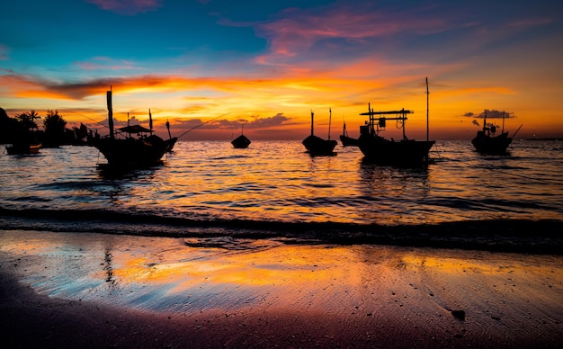 Silhouette of fishery wooden boat with warm and sunset low lighting dark shadow view.