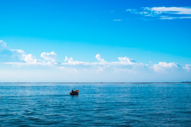 Silhouette fishing boat in the sea with blue sky