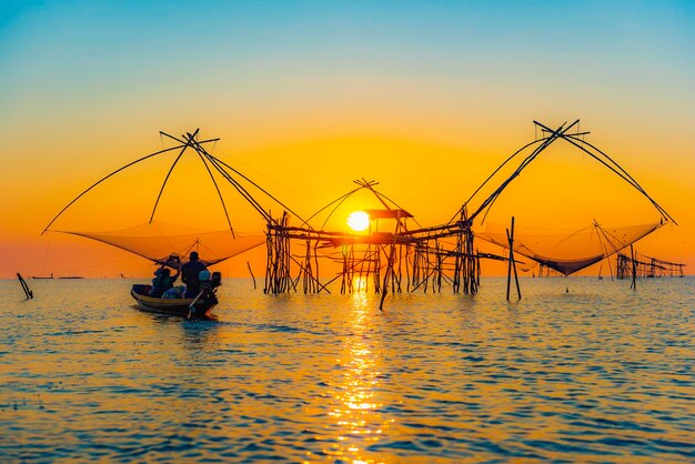 Photo silhouette fishing net on sea against sky during sunset