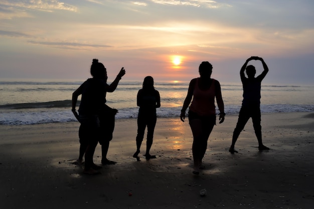 Silhouette of five people playing on the seashore at sunset Golden hour