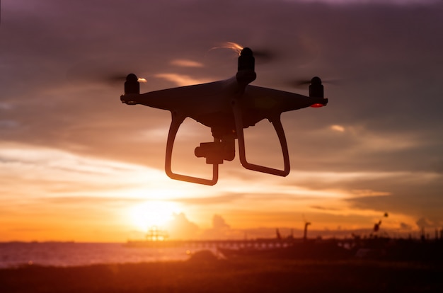 Silhouette of flying drone in sunset time.