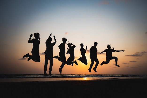 The silhouette of a friend jumping by the sea at sunset