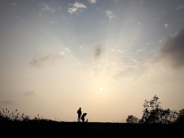 Foto silhouette di amici in piedi sul campo contro il cielo durante il tramonto