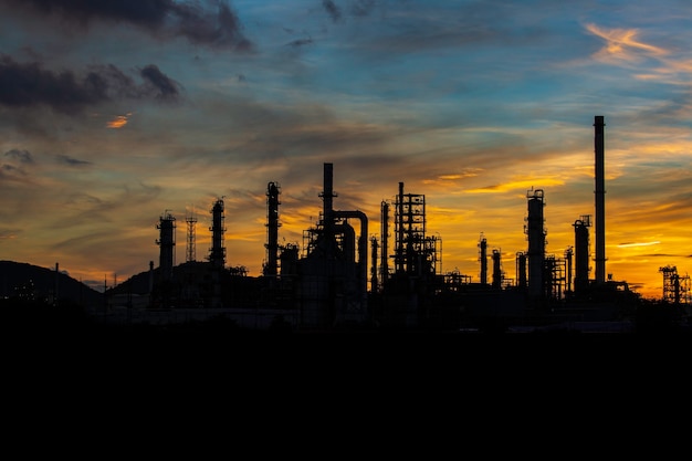 Silhouette di distillazione del gas della torre dell'impianto di raffineria di petrolio del serbatoio e dell'olio del serbatoio della colonna dell'industria petrolchimica sullo sfondo del tramonto del cielo
