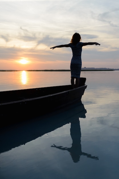 Foto siluetta di una ragazza su una barca su uno sfondo di tramonto