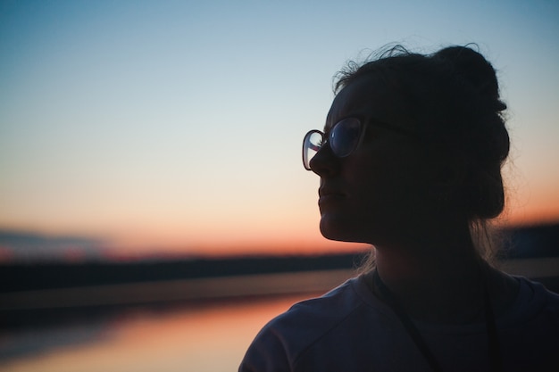 Silhouette girl in glasses sunset