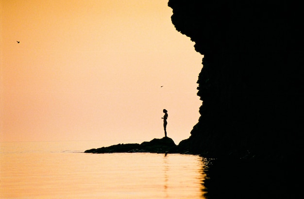 Silhouette of a girl near the sea at sunset