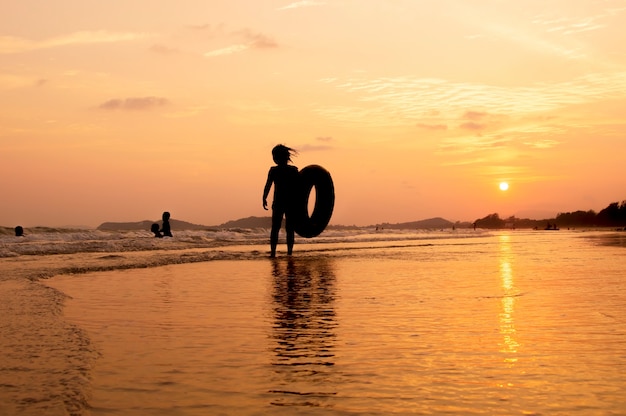 Siluetta della ragazza che gioca sulla spiaggia al tramonto