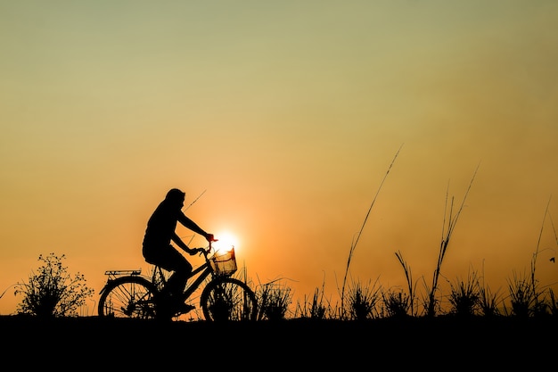 silhouette of a girl riding on a trail with his bike.