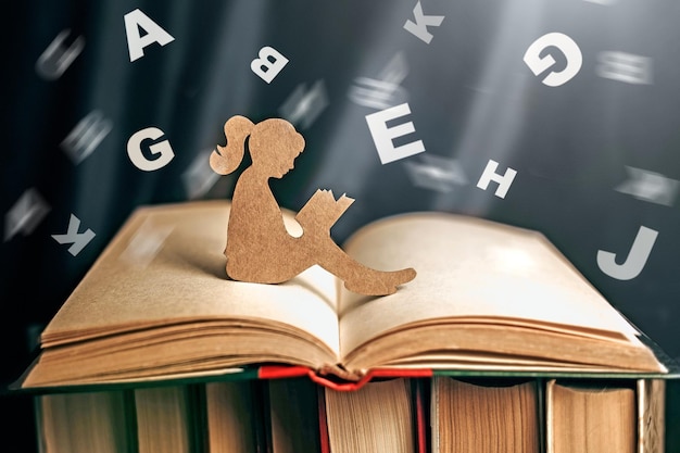 silhouette of a girl with dyslexia holds and reads a book Flying tangled letters in the air