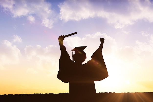 Silhouette of graduate against sun shining