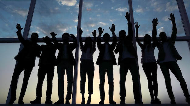 Silhouette of a group of business people raising their hand