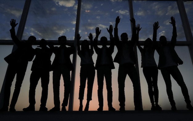 Silhouette of a group of business people raising their hand