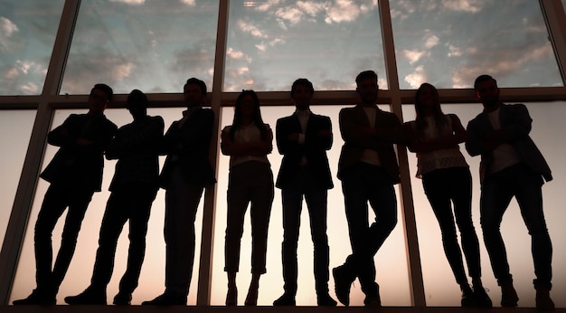 Силуэт группы деловых людей, стоящих у окна офиса, фото с копировальным пространством