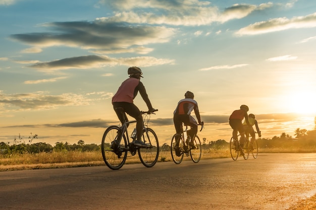 日没時に自転車に乗っている男性のシルエットグループ。