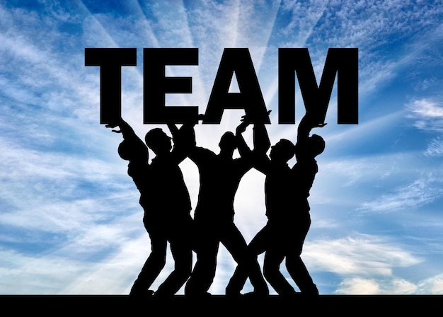 Silhouette of a group of men who hold the word team above themselves. The concept teamwork