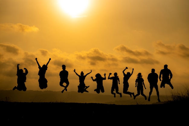 La silhouette di un gruppo di persone sta celebrando il successo in cima alla collina.