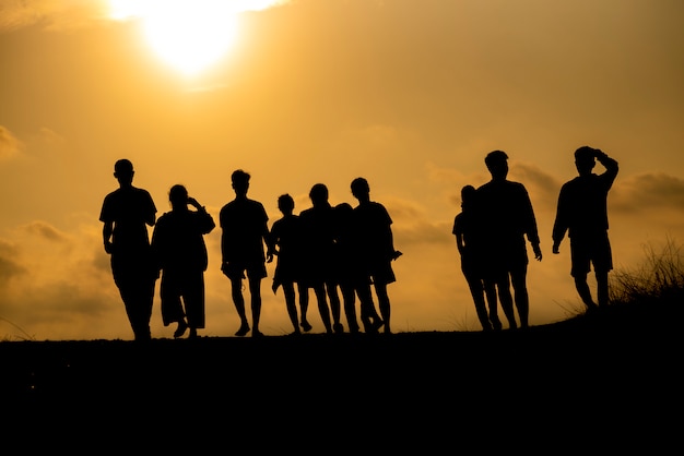 The silhouette of a group of people is celebrating success on the hilltop.