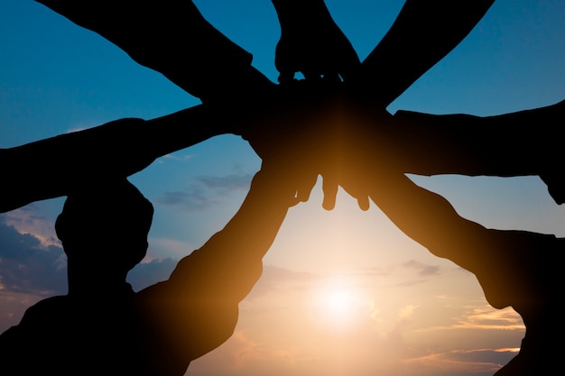  silhouette of group people putting hand together 