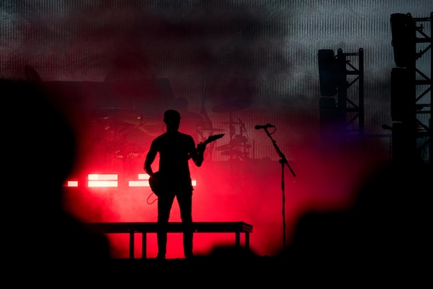 Silhouette of a guitarist in red stage lights