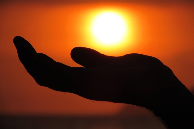 Foto silhouette mano contro il cielo durante il tramonto