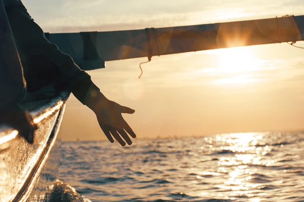 Silhouette of a hand from a boat on a sunset background