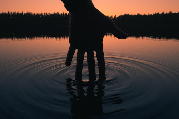 Photo silhouette of a hand touching the water surface human impact on the environment
