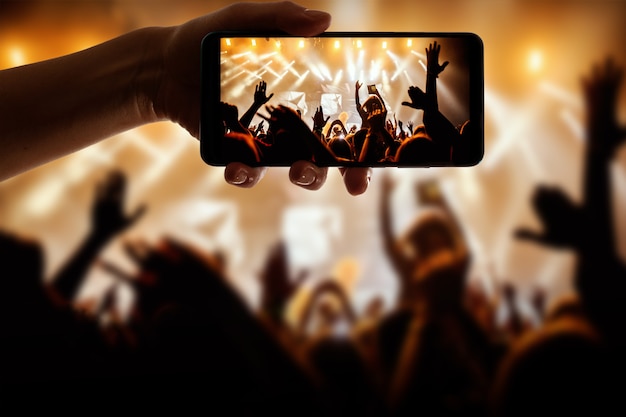 Silhouette of hand using camera phone to take pictures and
videos at pop concert, festival.