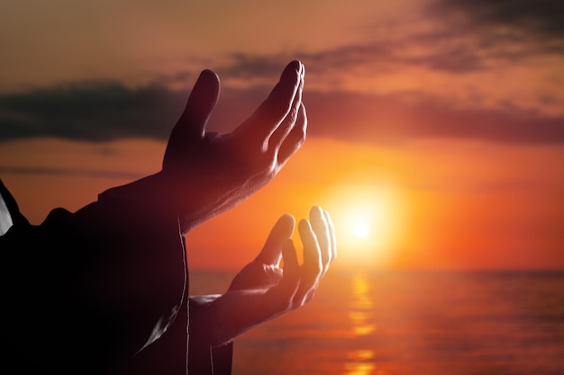 Foto silhouette di mani che pregano sullo sfondo del cielo