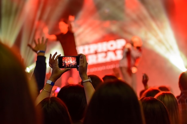 Silhouette of hands with a smartphone at a concert