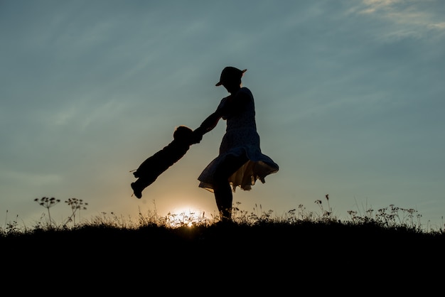 silhouette of happy family enjoying themselves on cliff