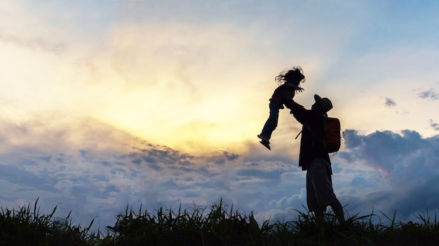 Silhouette of a happy family of father and child in front of a violet sky