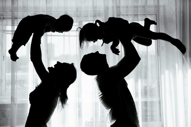 Silhouette of a happy family mother father and children have fun in the apartment
