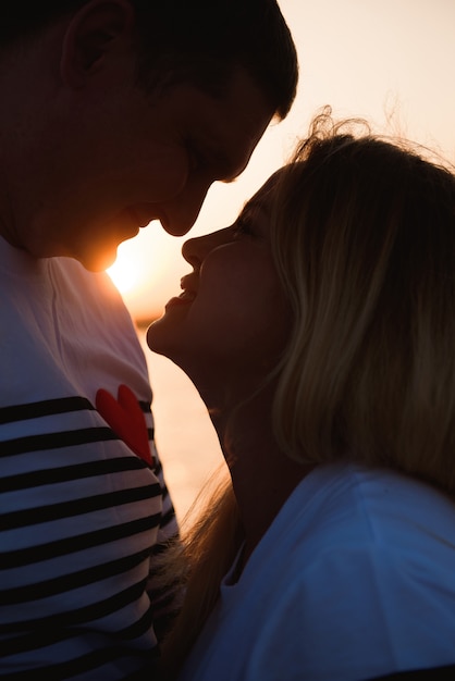 Silhouette di una famiglia felice, una madre incinta e il suo marito che si rilassano sul fiume