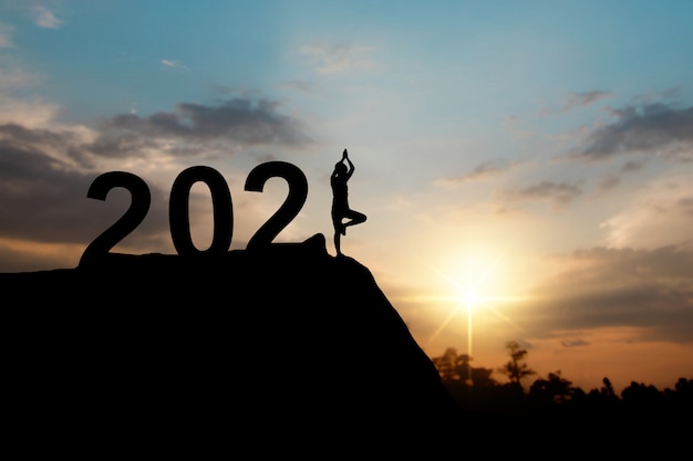 Silhouette di felice anno nuovo 2021 con donna che fa yoga