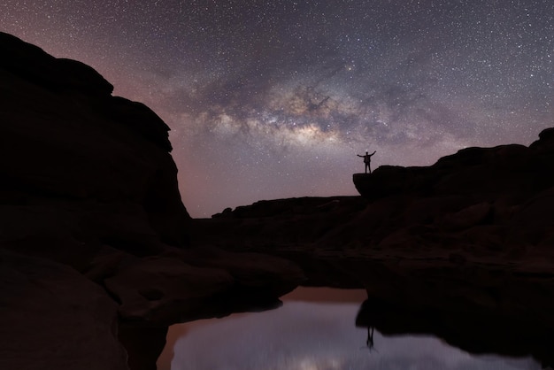 silhouette of happy people jumping over night sky with stars and Milky way galaxy Astronomy orient