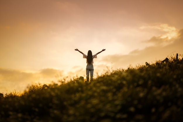 Foto silhouette di donna felice rilassante sulla collina di montagna nel cielo al tramonto estivo