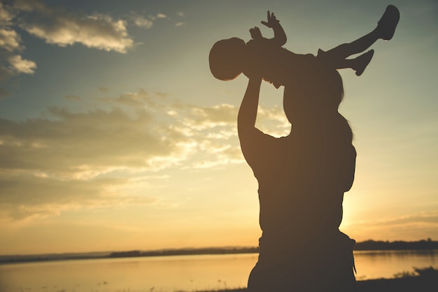 A silhouette of a happy young mother harmonious family outdoors.