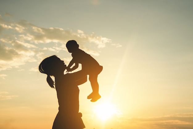 A silhouette of a happy young mother harmonious family outdoors