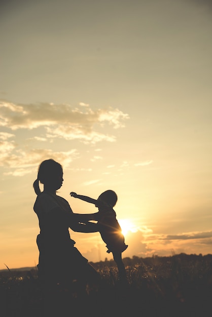 A silhouette of a happy young mother harmonious family outdoors. 