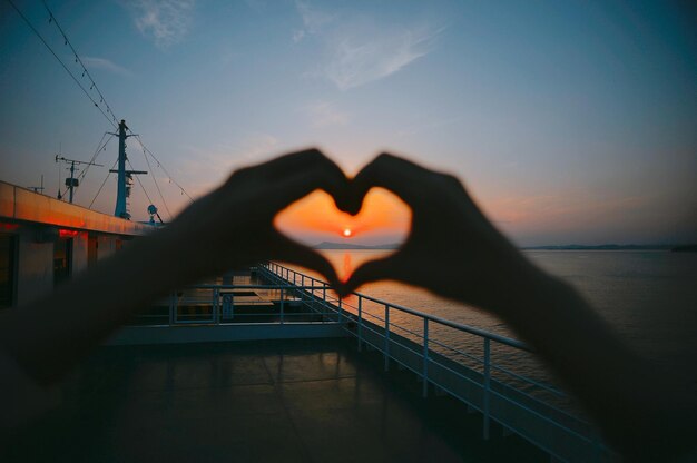 Foto silhouette a forma di cuore con una ringhiera contro il cielo durante il tramonto