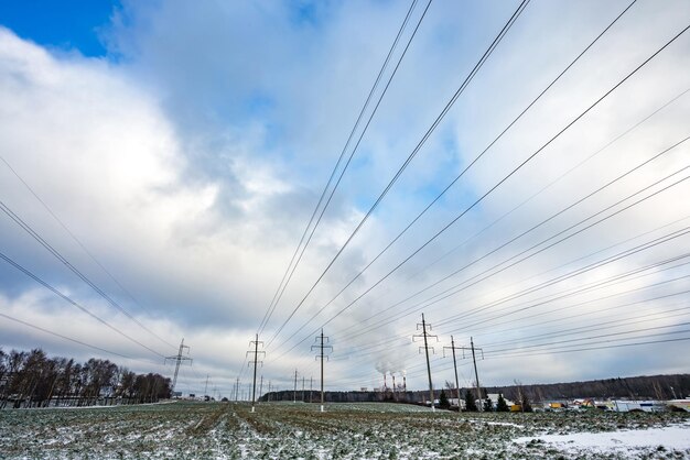 Silhouette of the high voltage electric pylon towers on the background of beautiful clouds steaming pipes of a thermal power plant