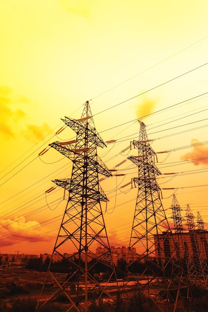 Silhouette of highvoltage electrical towers on a sunset background