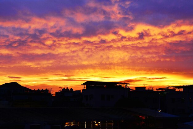 Silhouette houses against orange sky