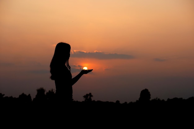 夕日を背景に願い事をするために上げられた人間の手のシルエット